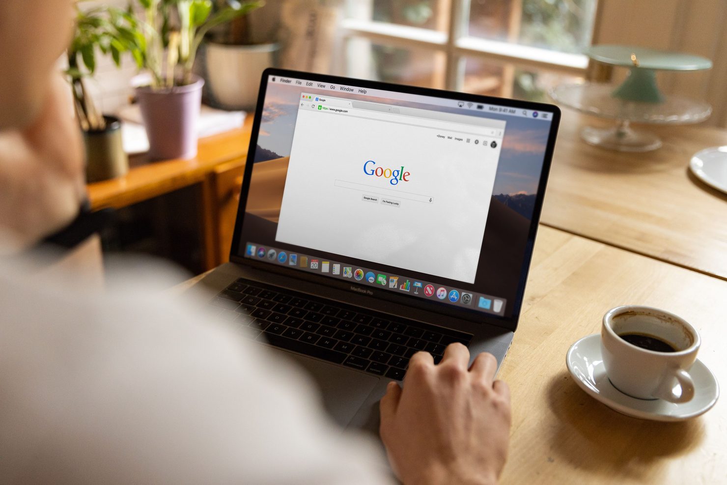 A person sitting at a laptop with the Google homepage open, about to start a search