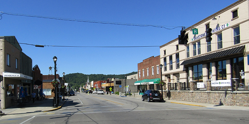 Main Street in historic downtown Morehead, Kentucky with local shops and Appalachian hills in the distance